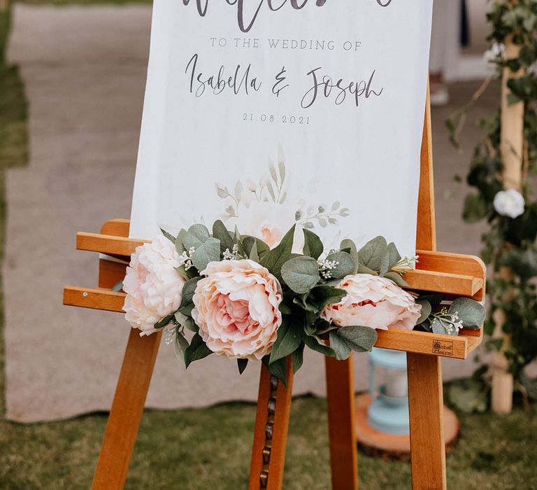 Welcome sign complete with florals set on wooden easel outdoors