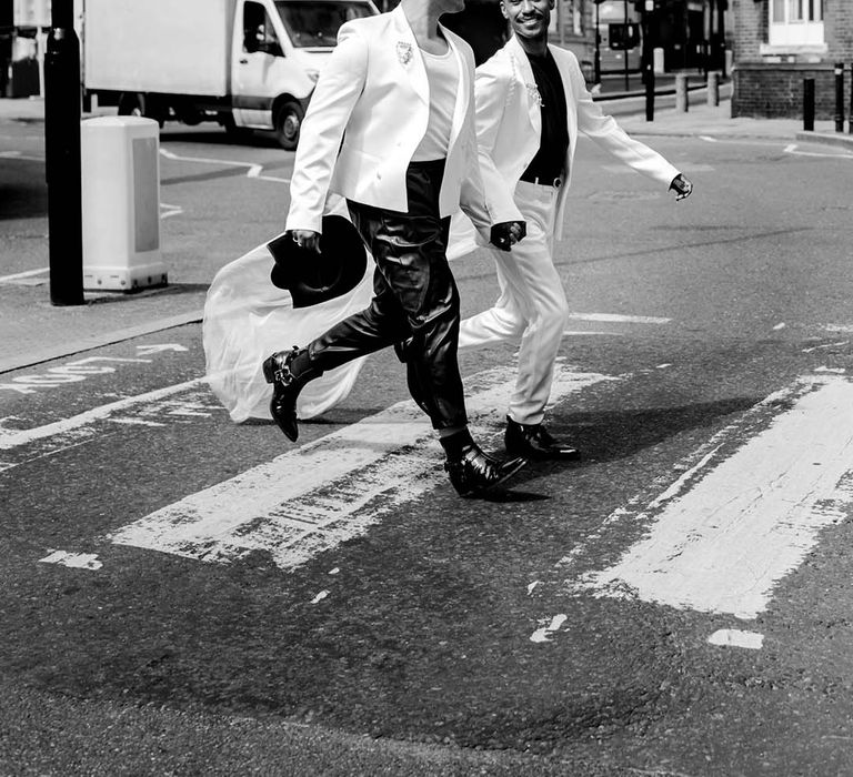 two stylish grooms crossing the road in monochrome suits 