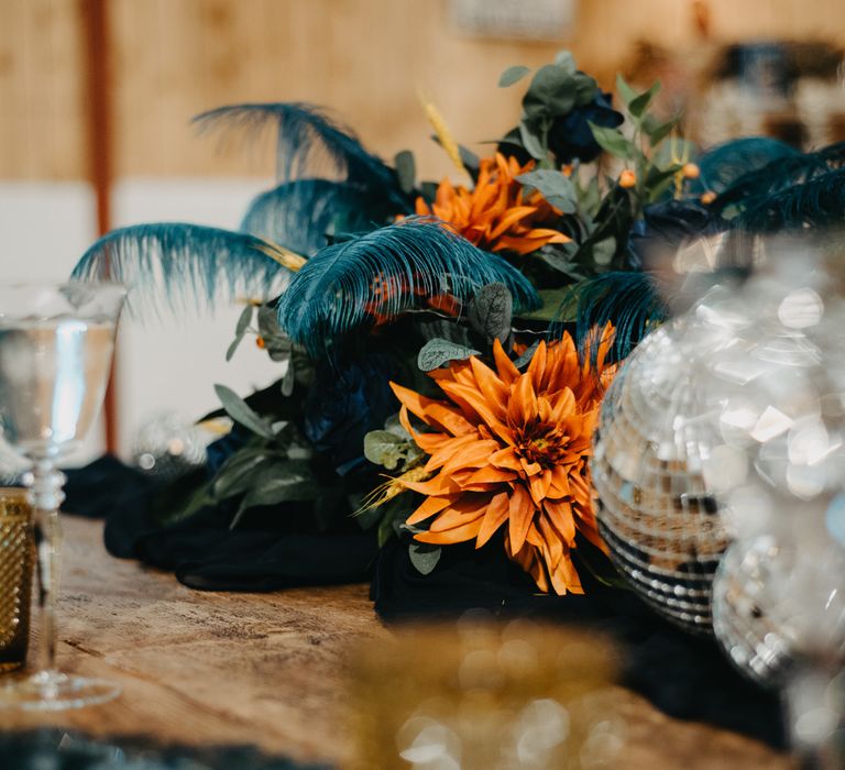 Orange, blue and green floral centrepiece with disco balls and rustic tableware for Wellbeing Farm wedding in Lancashire