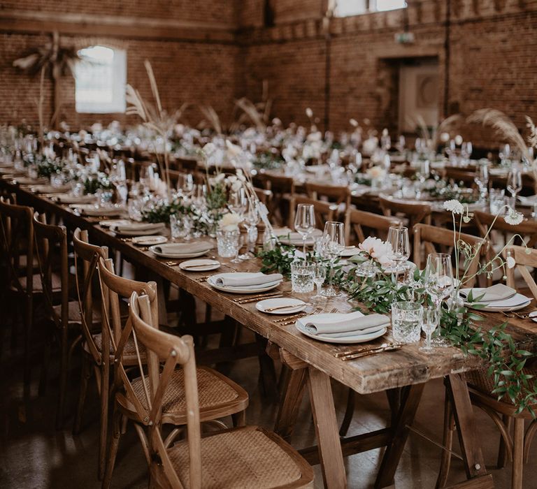 Godwick Barn complete with rustic wooden tables, green foliage and festoon lighting above