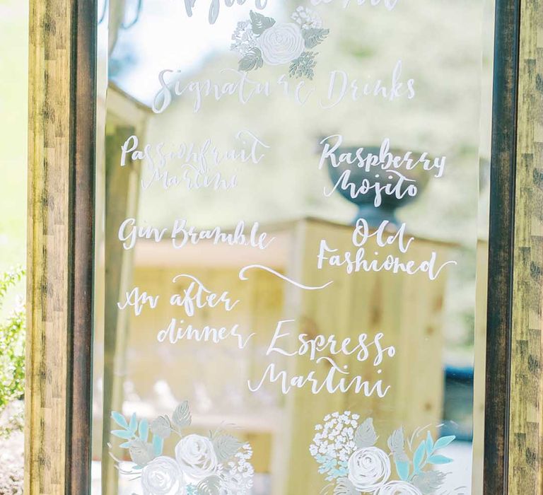 mirror wedding sign with cocktail menu written in white ink 