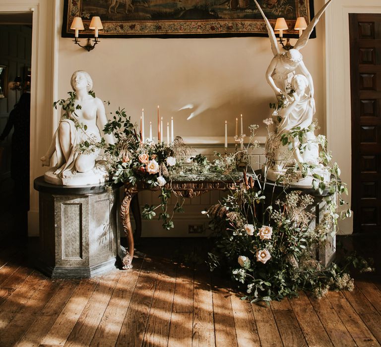 Green foliage and pink rose floral arrangement with taper candles decorating Elmore Court 