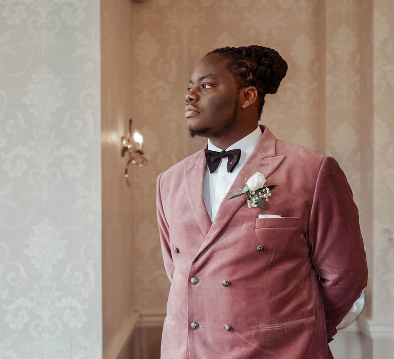 Groom wears dusky pink suit on his wedding day complete with floral buttonhole 