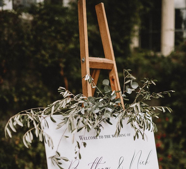 Monochrome wedding sign on wooden stand with foliage decor