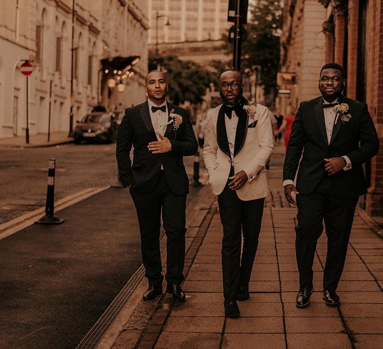 Groomsmen in black tuxedos and groom in a white brocade tuxedo jacket with black lapel at Birmingham wedding 