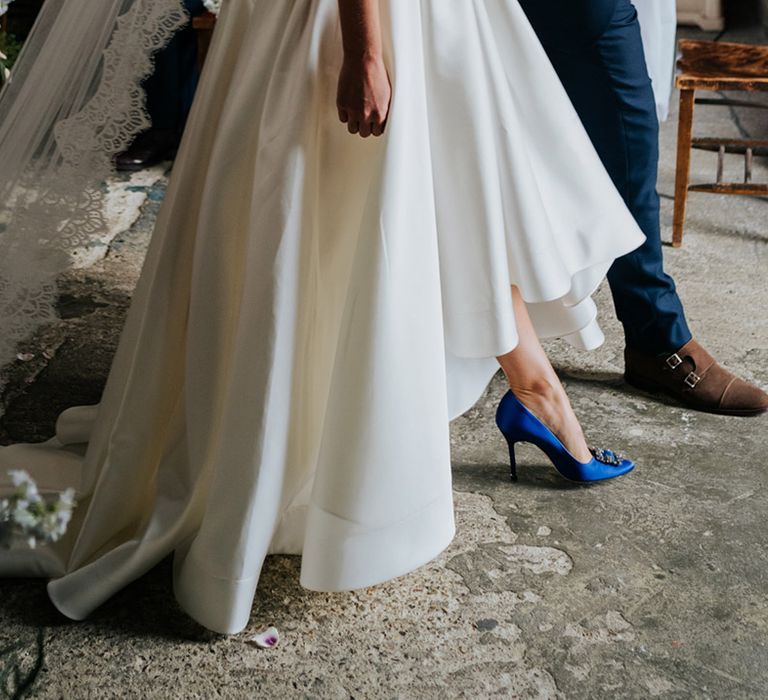 Bride in high low wedding skirt to show off electric blue wedding heels and long lace detail veil 