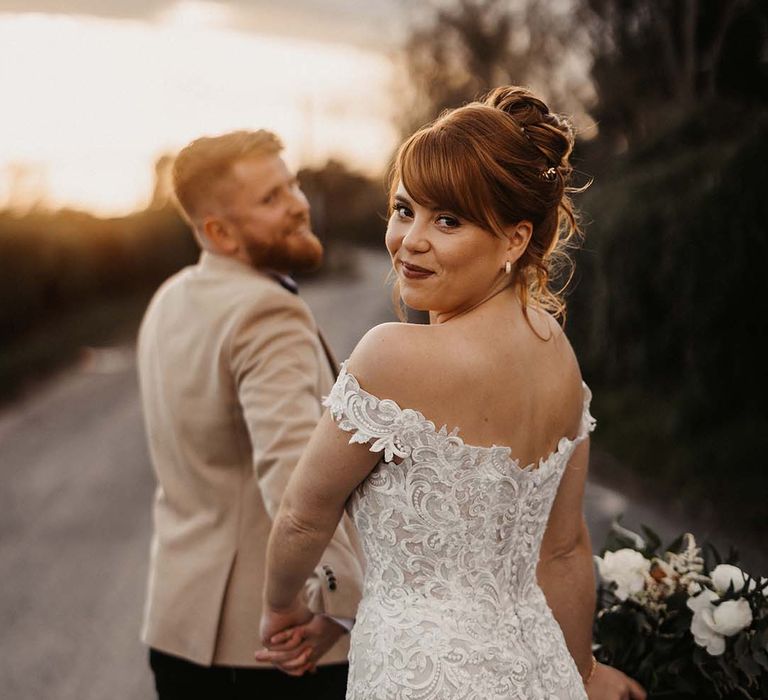 Bride wearing curled updo and lace wedding dress from Maggie Sottero with button details 