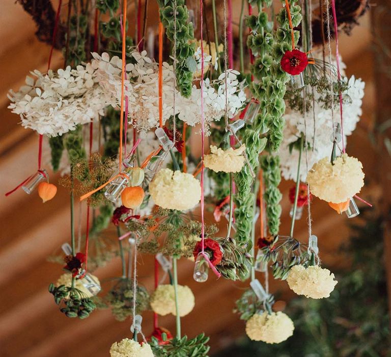 Hanging plant wedding decor from twisted wooden ring with white, yellow and orange flowers including hydrangea 