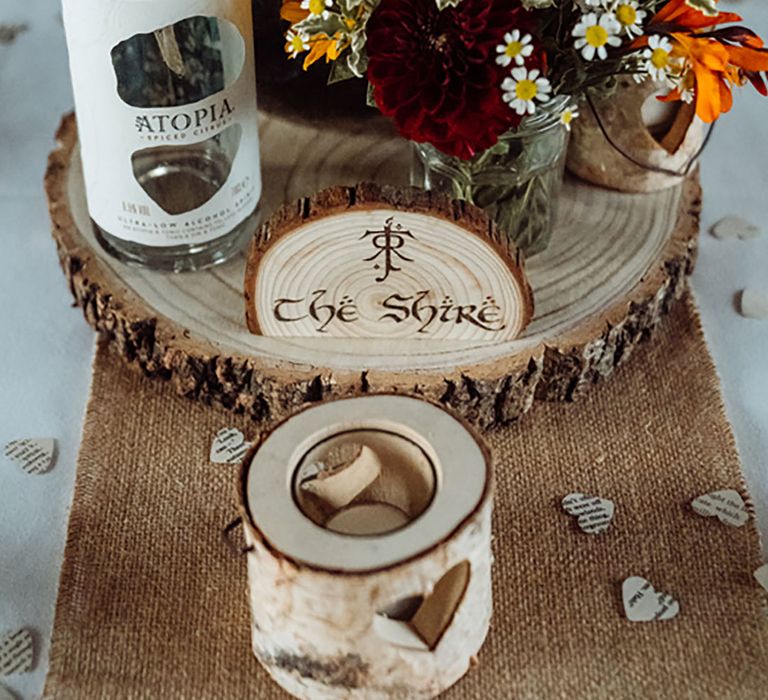 Wood slice table centrepiece decor with fictional place from a film name for quirky table setting decor with flowers on tree trunk stand 