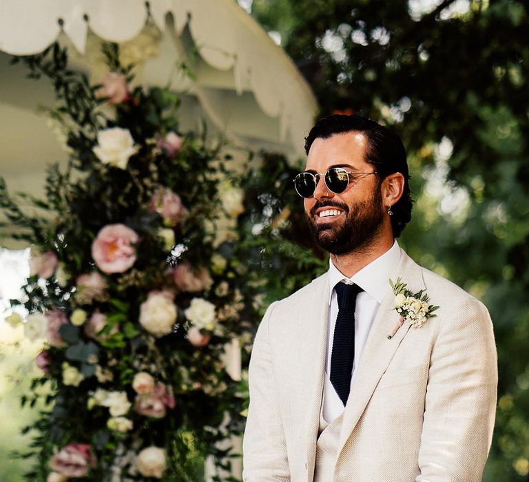 Groom in a beige suit wearing sunglasses at Preston Court outdoor wedding ceremony 