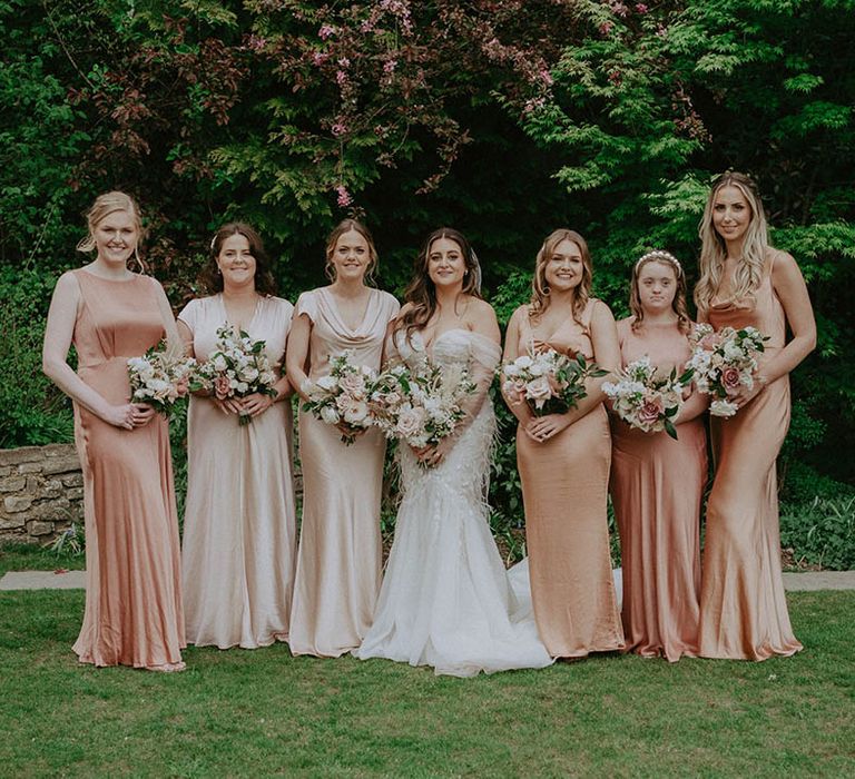 Bride in feather wedding dress with tulle skirt with bridesmaids in satin dresses bridal party shot 