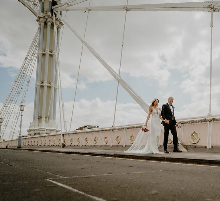 Bride and groom walk across a bridge in London after their registry city wedding 