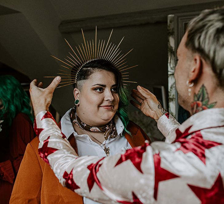 Groom places gold crown on wedding guests head on the morning of his wedding day