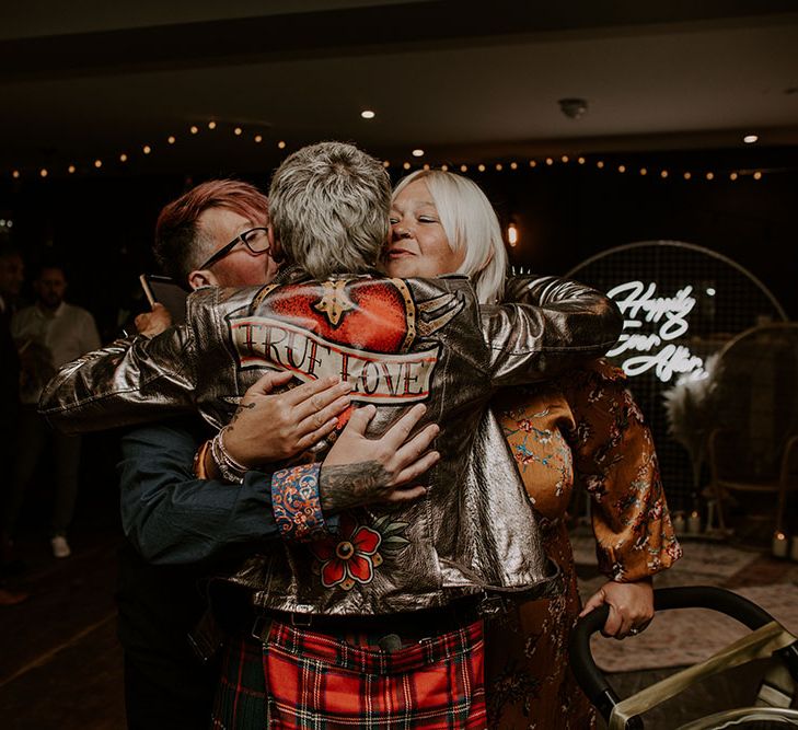 Groom wears True Love gold leather jacket and hugs wedding guests 