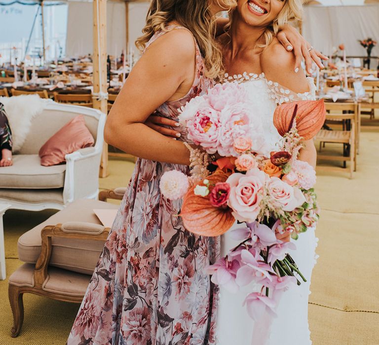 Smiling happy bride gets a kiss and embrace from one of the bridesmaids 