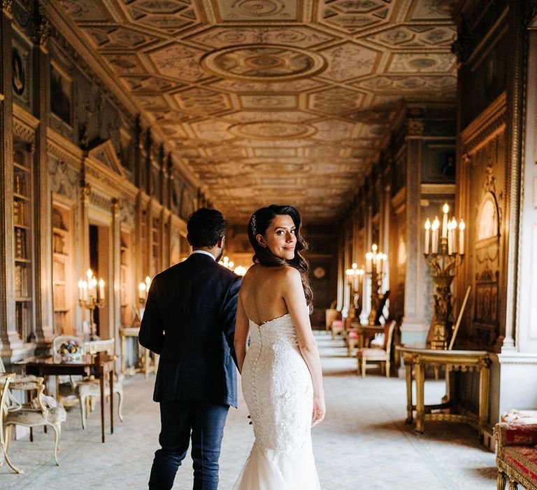 Bride wears fitted lace mermaid wedding dress and walks alongside her groom 