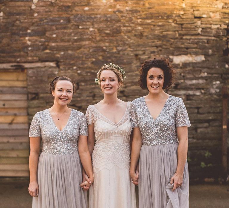 Bride in a beaded wedding dress and flower crown with the bridesmaids in grey dresses and sequin tops 