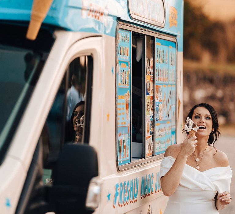 Bride in an off the shoulder wedding dress eating an ice cream from an ice cream van