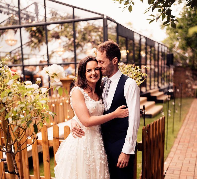 Bride in applique Phillipa Lepley wedding dress with the groom in a blue waistcoat and trousers for their glass marquee reception 