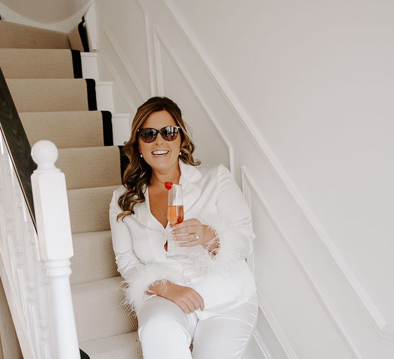 Bride wears sunglasses and white silk pyjamas complete with fluffy cuffs 