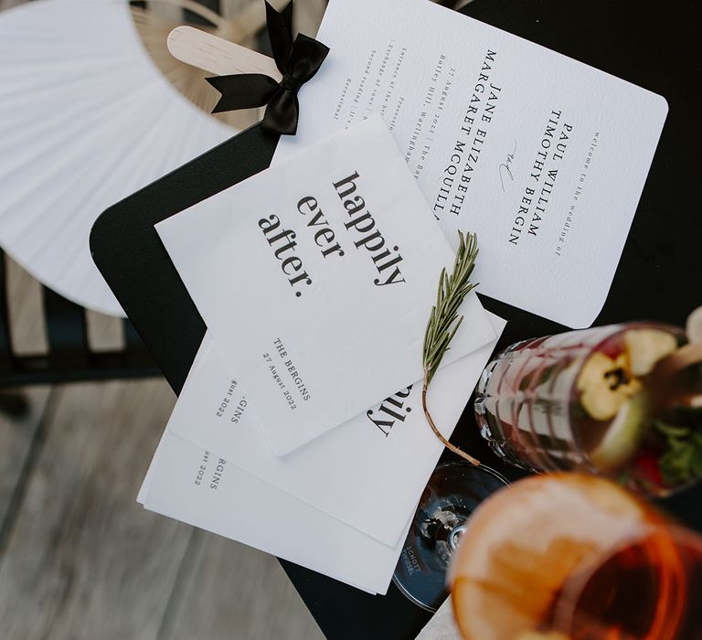 Modern white wedding stationery beside colourful drink