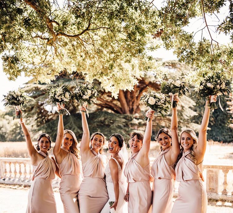 The bridesmaids all wear matching halter neck satin pink dresses with the bride in a fitted lace wedding dress