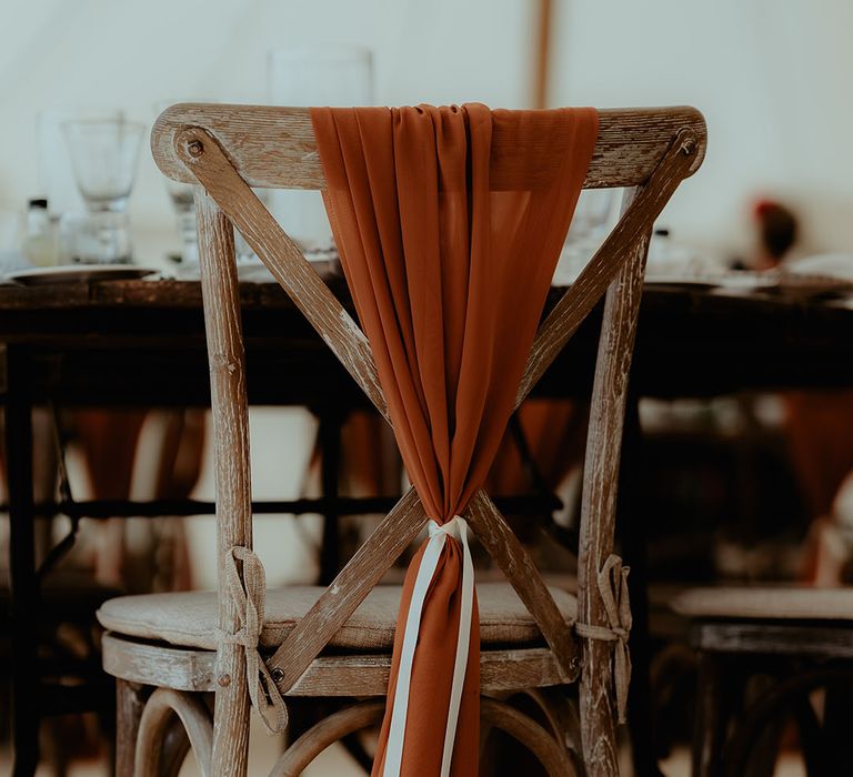 Autumnal orange wedding sash decorating the chairs at a marquee wedding 