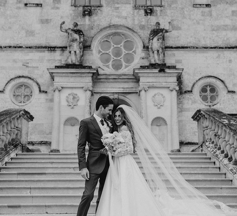 Bride and groom stand on the steps together at their castle wedding venue in Dorset 