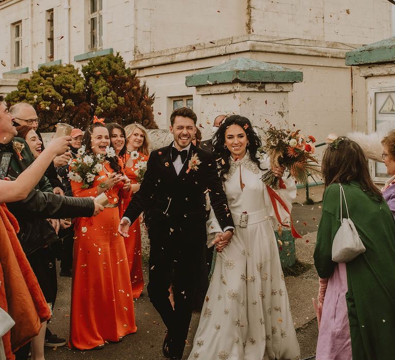 The bride and groom have fun confetti exit after their ceremony at the vintage retro wedding with 70s theme 