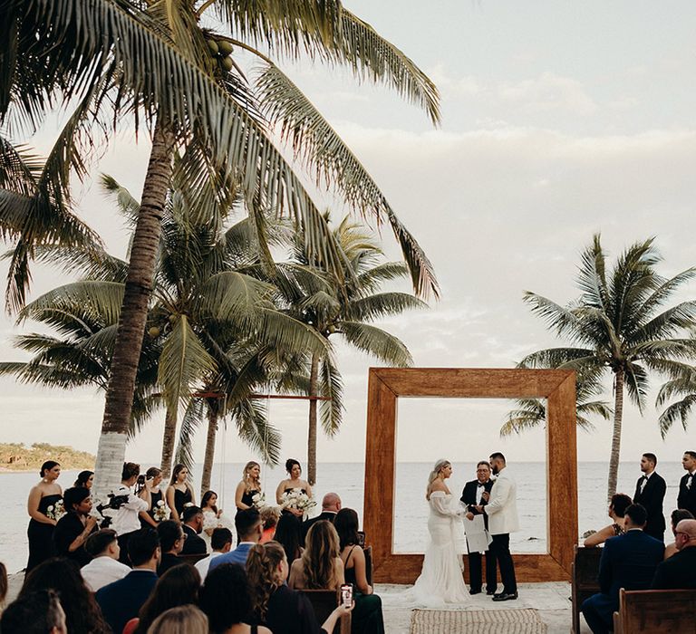 blue venado beach wedding ceremony in front of the ocean with wooden frame altar decorations and palm trees