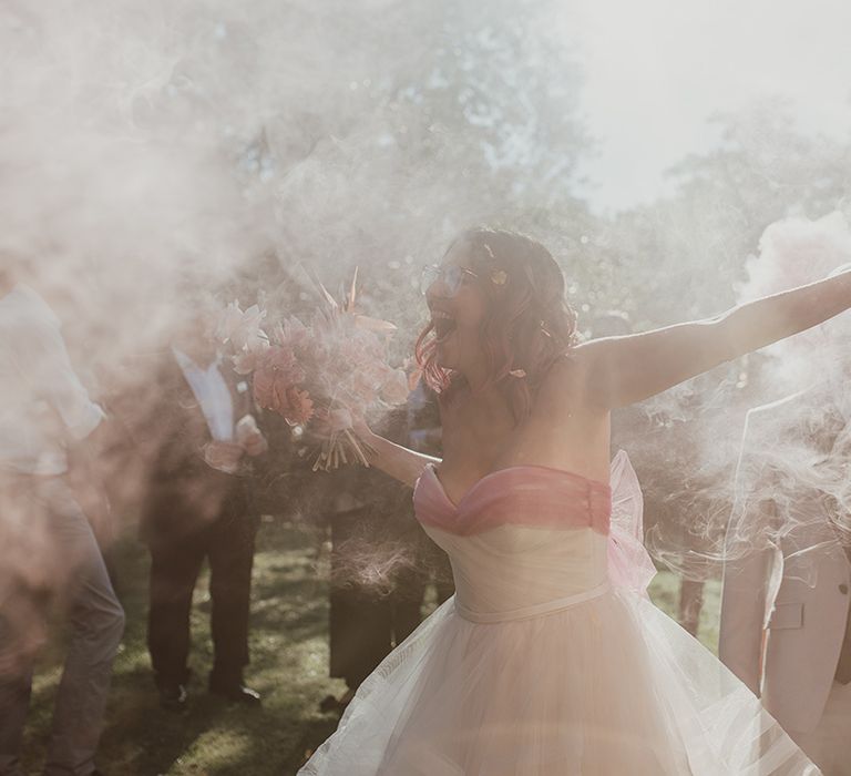 bride in a strapless princess wedding dress with pink bow dancing in the smoke flare clouds