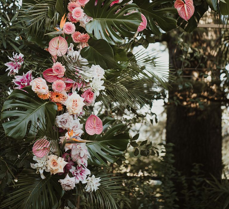 tropical pink and green wedding flower arch with anthuriums and palm leaves