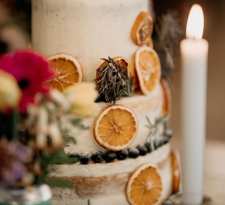 Stunning rustic wedding cake with semi-naked frosting and dried orange slice decorations 