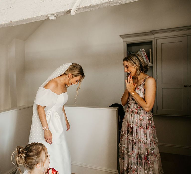 Bridesmaids in mismatched bridesmaid dresses help the bride with the finishing touches as she gets ready for the day 