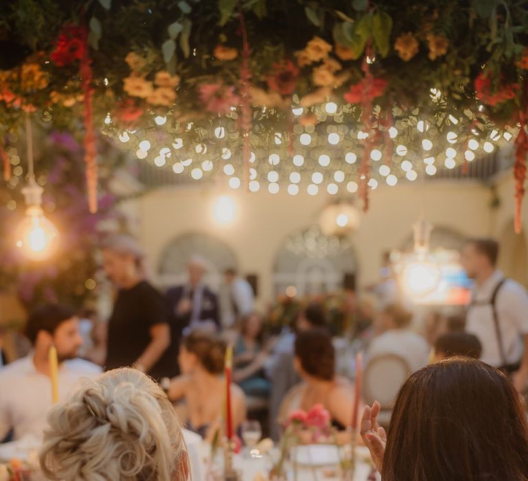 blonde bride with back tattoo with loosely pinned wedding up do sitting next to her bride with long wavy wedding hair 