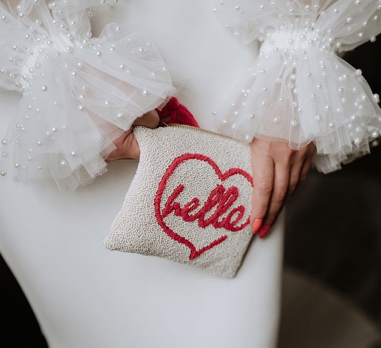 Bride holding a pearl bridal clutch with heart design for on the day accessories 