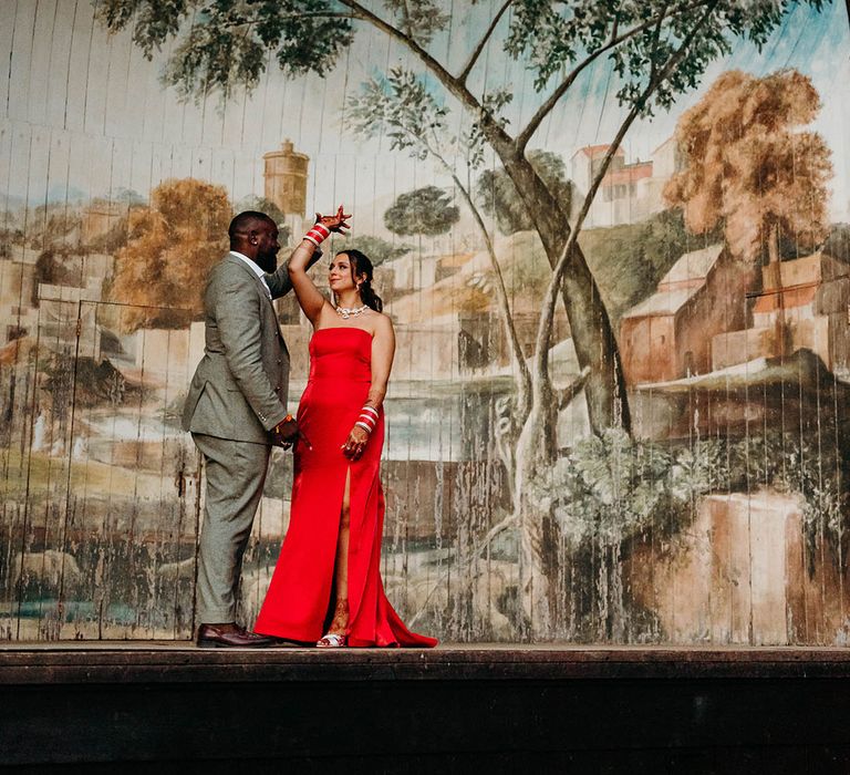 The bride in a strapless red wedding reception dress on stage with the groom 