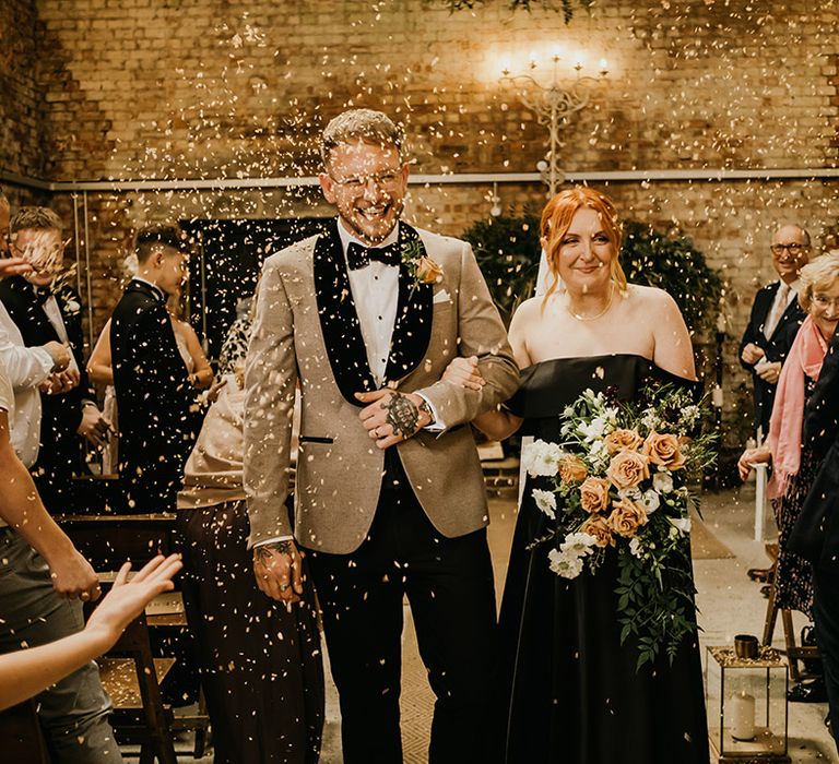 Confetti moment for bride in black wedding dress walking back down the aisle with the groom as a married couple 