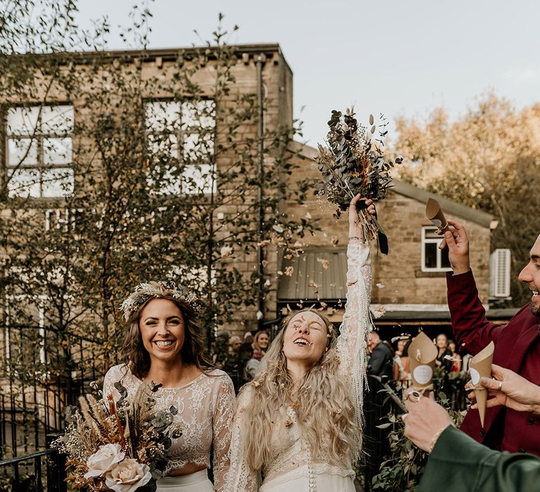 Bowers Mill wedding in Yorkshire with two brides in lace wedding dresses having fun confetti moment 