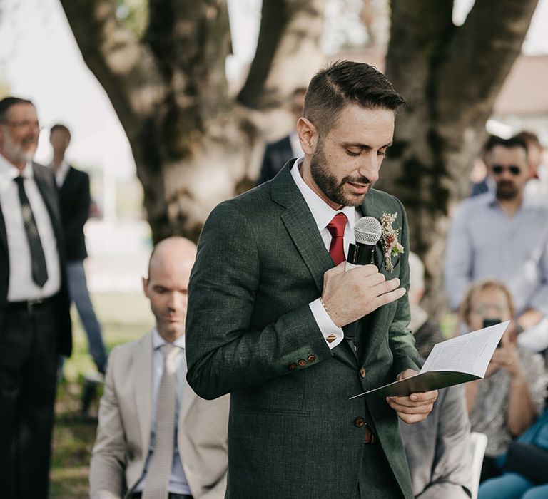 groom reading his personalised wedding vows during the outdoor wedding ceremony 