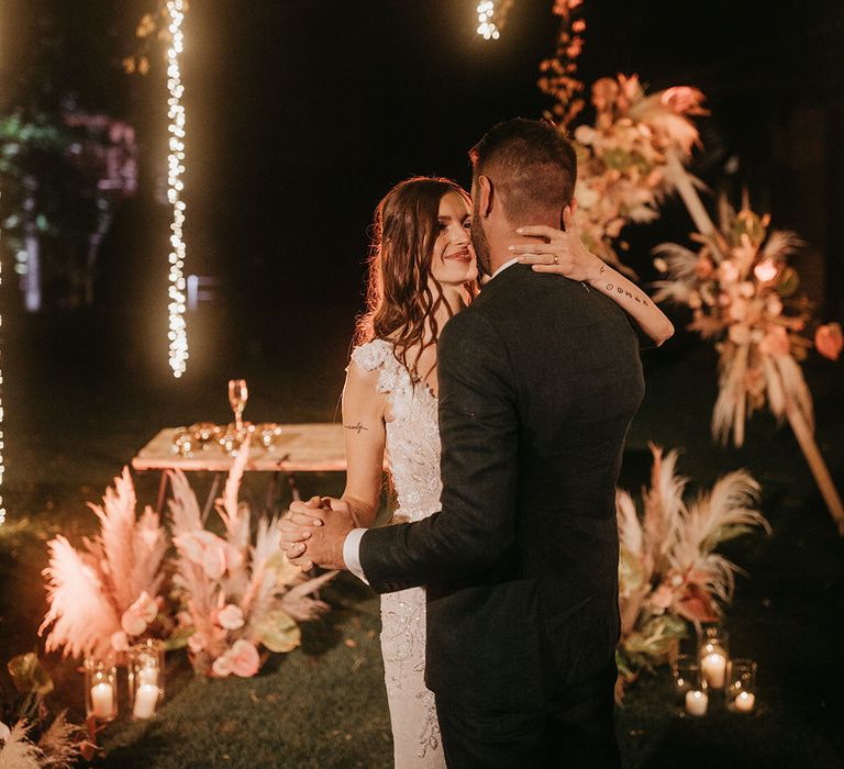 outdoor first dance with string lights and pampas grass decor 