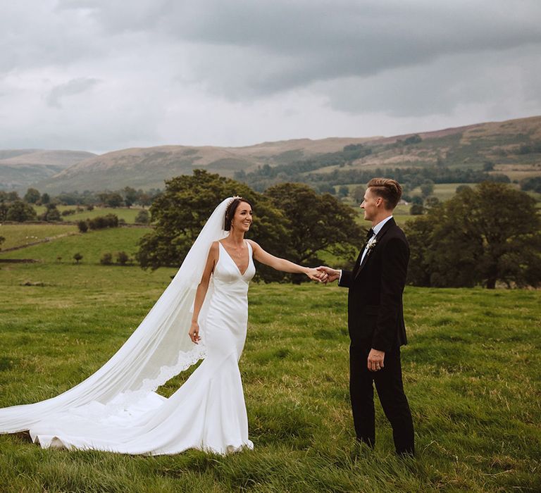 Bride in satin slip wedding dress with cathedral length embroidered edge veil 