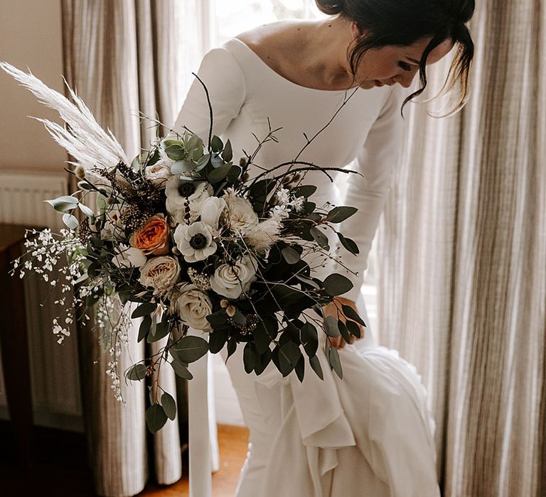 Bride wearing a long sleeve wedding dress holding a white wedding bouquet for the winter wedding 