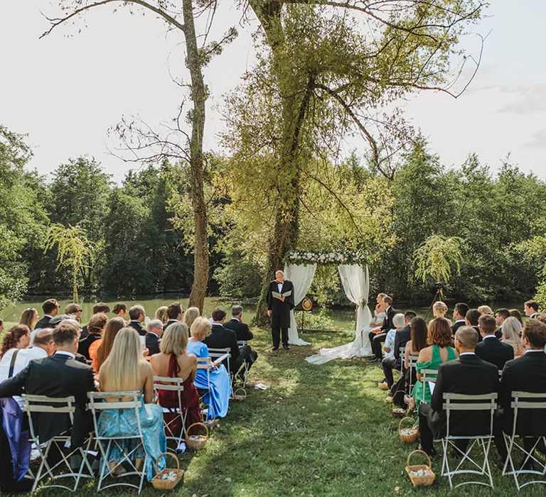 Destination wedding in France with outdoor wedding ceremony as guests sit either side of the aisle 