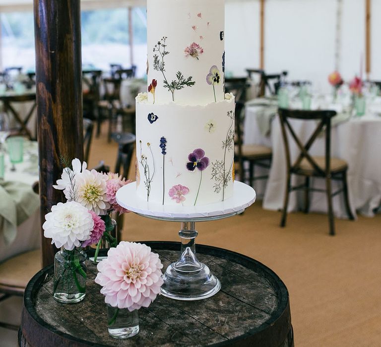 Three tier white buttercream frosted wedding cake with pressed wildflowers 