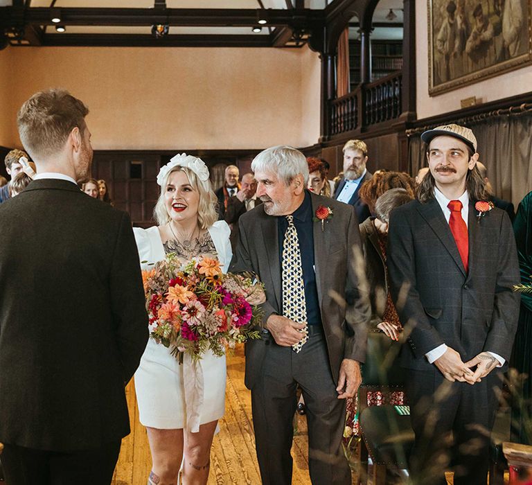 Father of the bride walks the bride in a short wedding dress down the aisle at town hall wedding 