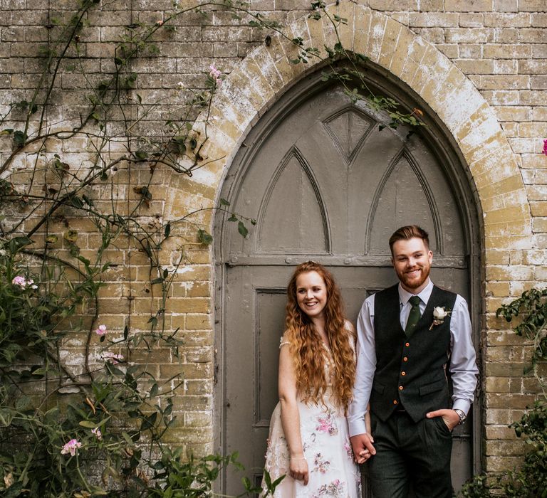 Bride & groom in front of door with foliage 