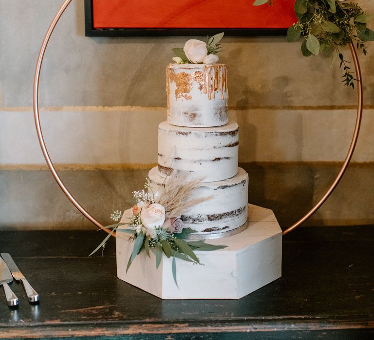 Three tier white and gold wedding cake with cake hoop and white rose 