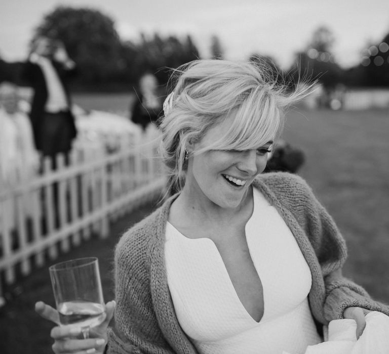 Bride with a fringe dancing in a field in a wedding dress with plunging neckline and cardigan 