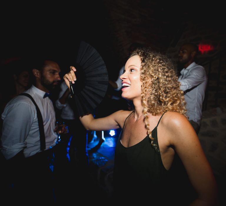 A guest fanning herself to cool down at the wedding after party